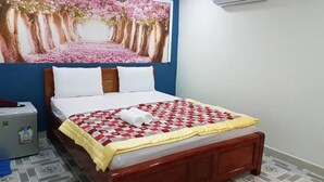 A bedroom with a bed, a nightstand, a wall-mounted air conditioner, and a large floral painting above the bed. - New Paris Hotel - by Bay Luxury (Ho Chi Minh City)