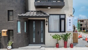 A modern building with a dark facade, a tiled entrance, and potted plants. - Penghu Lemongrass Easy Stay (Magong)