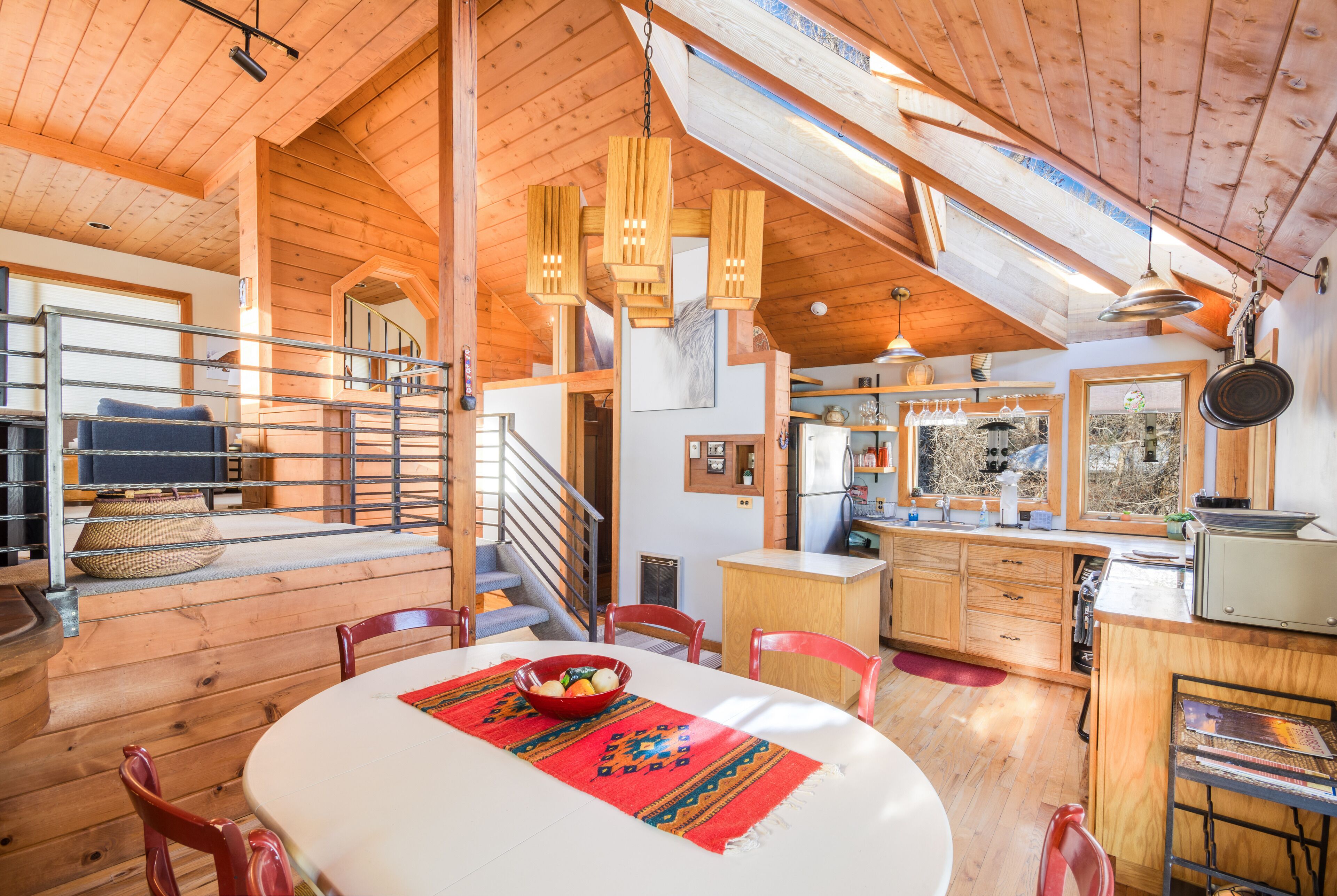 A wooden interior with a dining area, kitchen, and a staircase.