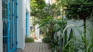 Un étroit sentier en bois mène à un bâtiment dont les fenêtres sont encadrées de bleu.
