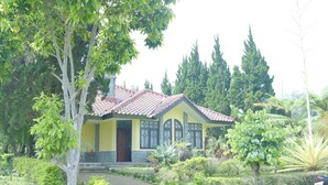 A house with a tiled roof, a yellow facade, and a stone foundation. - Villa ChavaMinerva Hanni Ciater with Pool (Ciater)