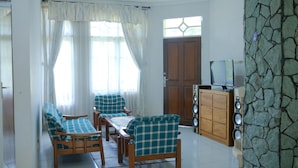 A living room with a sofa set, a wooden cabinet with speakers, and a stone wall. - Villa ChavaMinerva Hanni Ciater with Pool (Ciater)