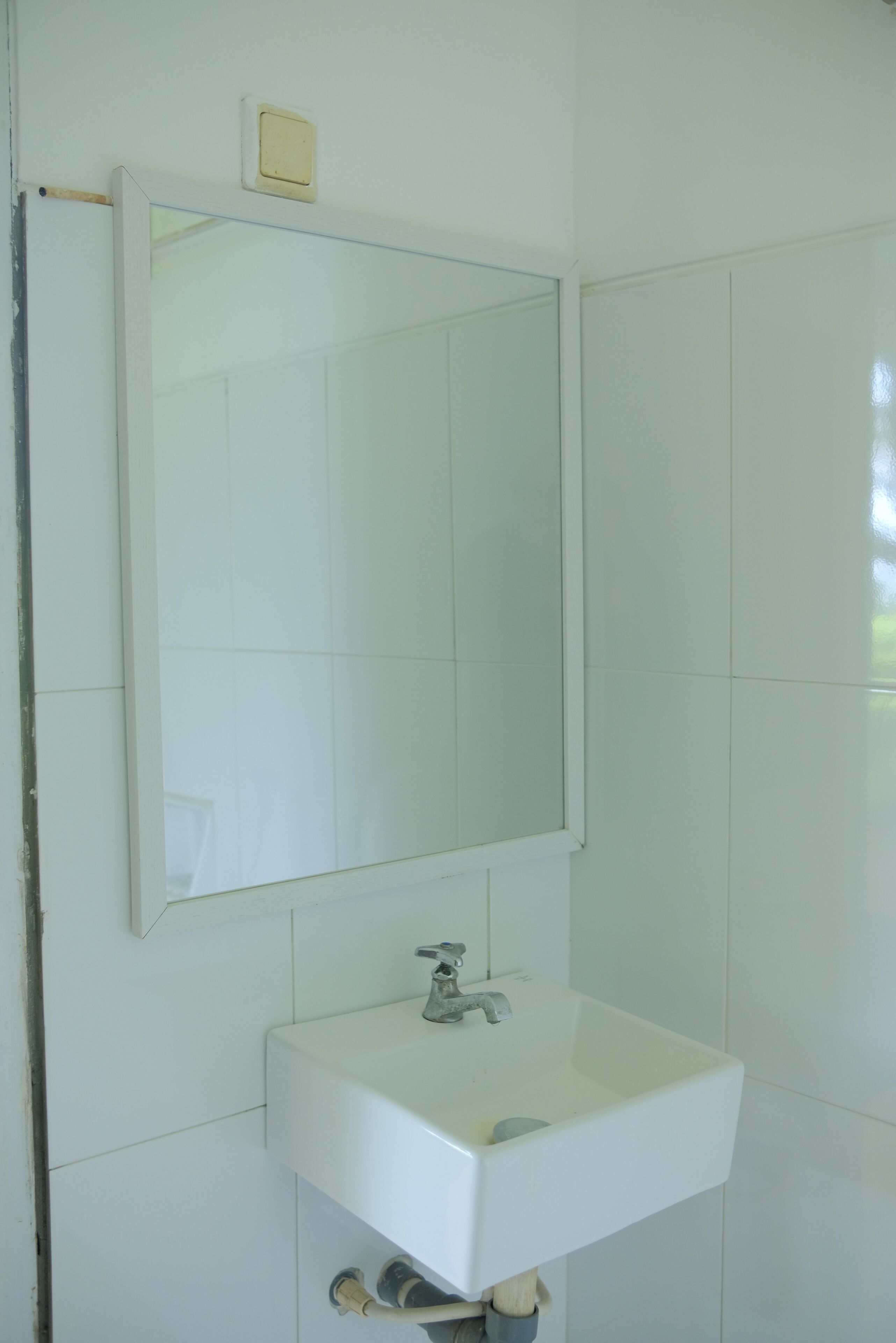 Ein Badezimmer mit einem weißen Waschbecken, einem Spiegel und einem kleinen Schrank darüber.