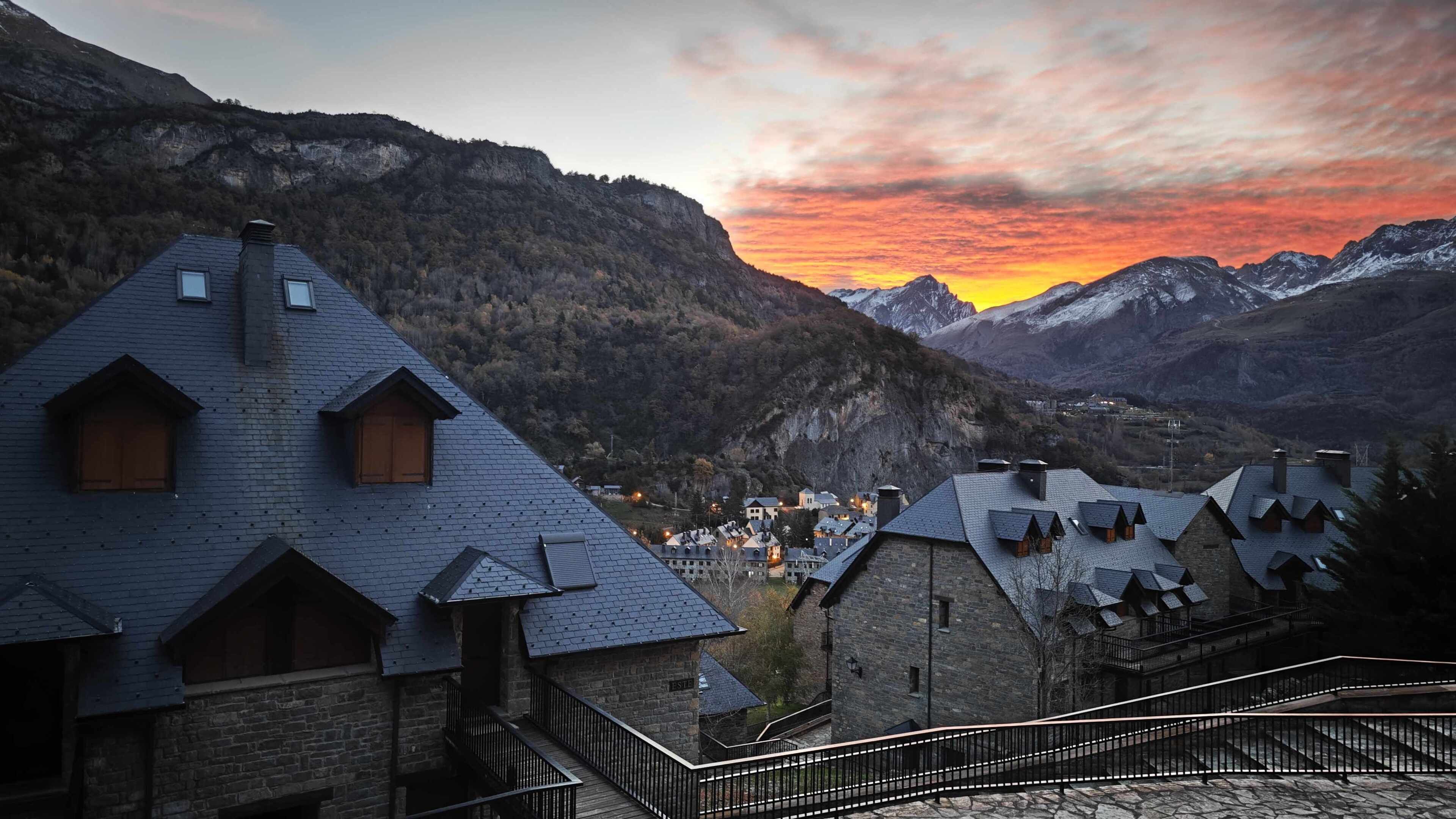 A mountain village with traditional chalet-style buildings, stone staircases, and a view of the surrounding mountains.