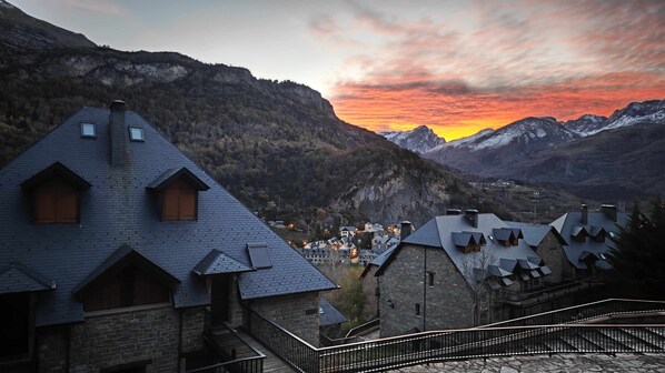 A mountain village with traditional chalet-style buildings, stone staircases, and a view of the surrounding mountains.