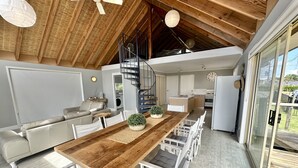 A modern kitchen with a wooden table, white chairs, and a built-in stove. - Betty on Bayview - Surf Beach  (Surf Beach)