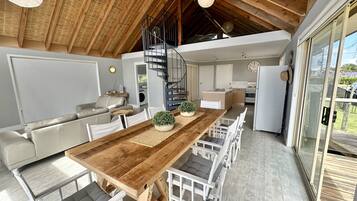 Une cuisine moderne avec une table en bois, des chaises blanches et une cuisinière encastrée.