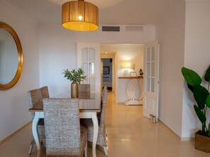 A dining area with wicker chairs, a white table, and a hanging light fixture. - Suitur cozy apartment with swimming pool and great views (MARBELLA)