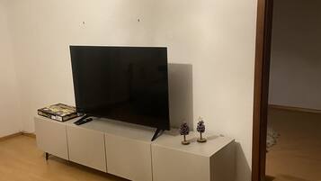 Una habitación con un armario blanco, un televisor encima y una puerta a la derecha.