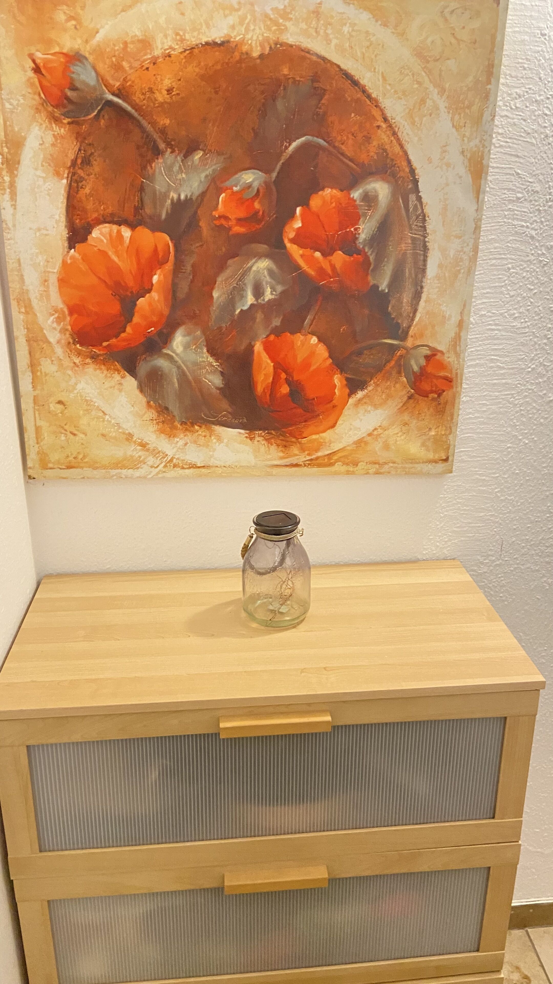 A wooden cabinet with two drawers and a glass jar on top.