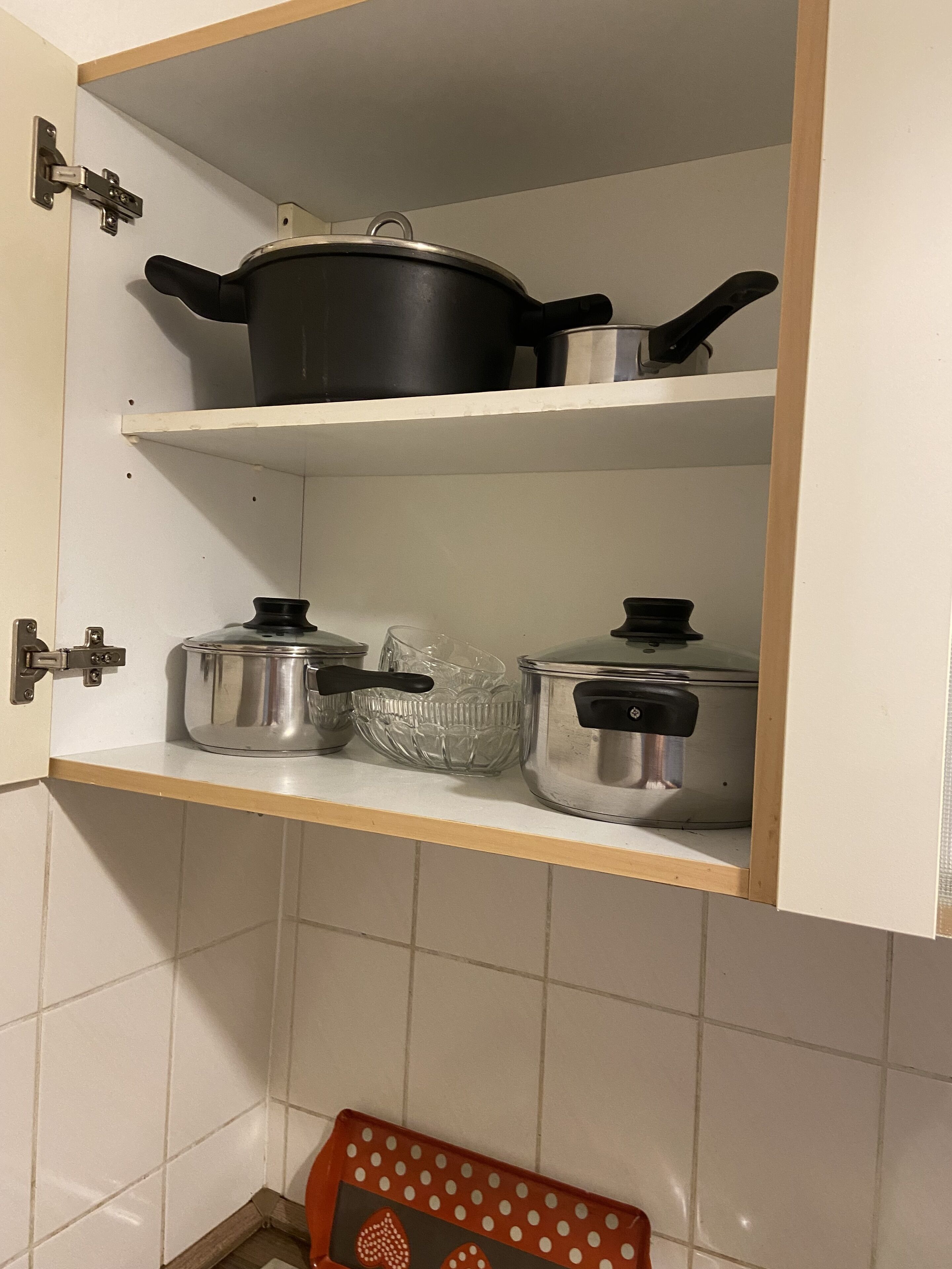 A kitchen with white cabinets, a wooden shelf, and a red tray with white polka dots.