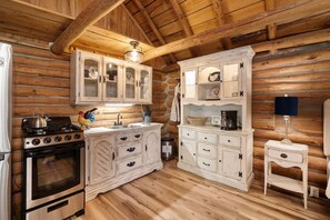 A rustic kitchen with wooden walls, a stove, cabinets, and a sink. - The Velvet Rooster – Cozy Cabin Stay with Pasture Views & Modern Comforts (Rudy)