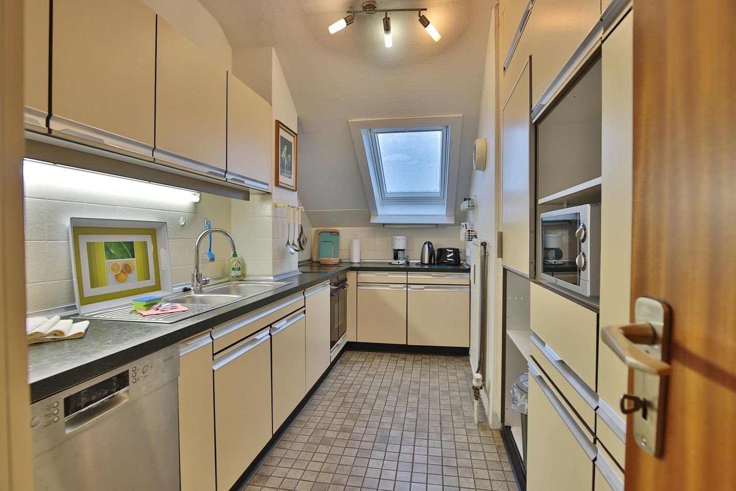 A compact kitchen with a window, a sink, a stove, and a microwave.