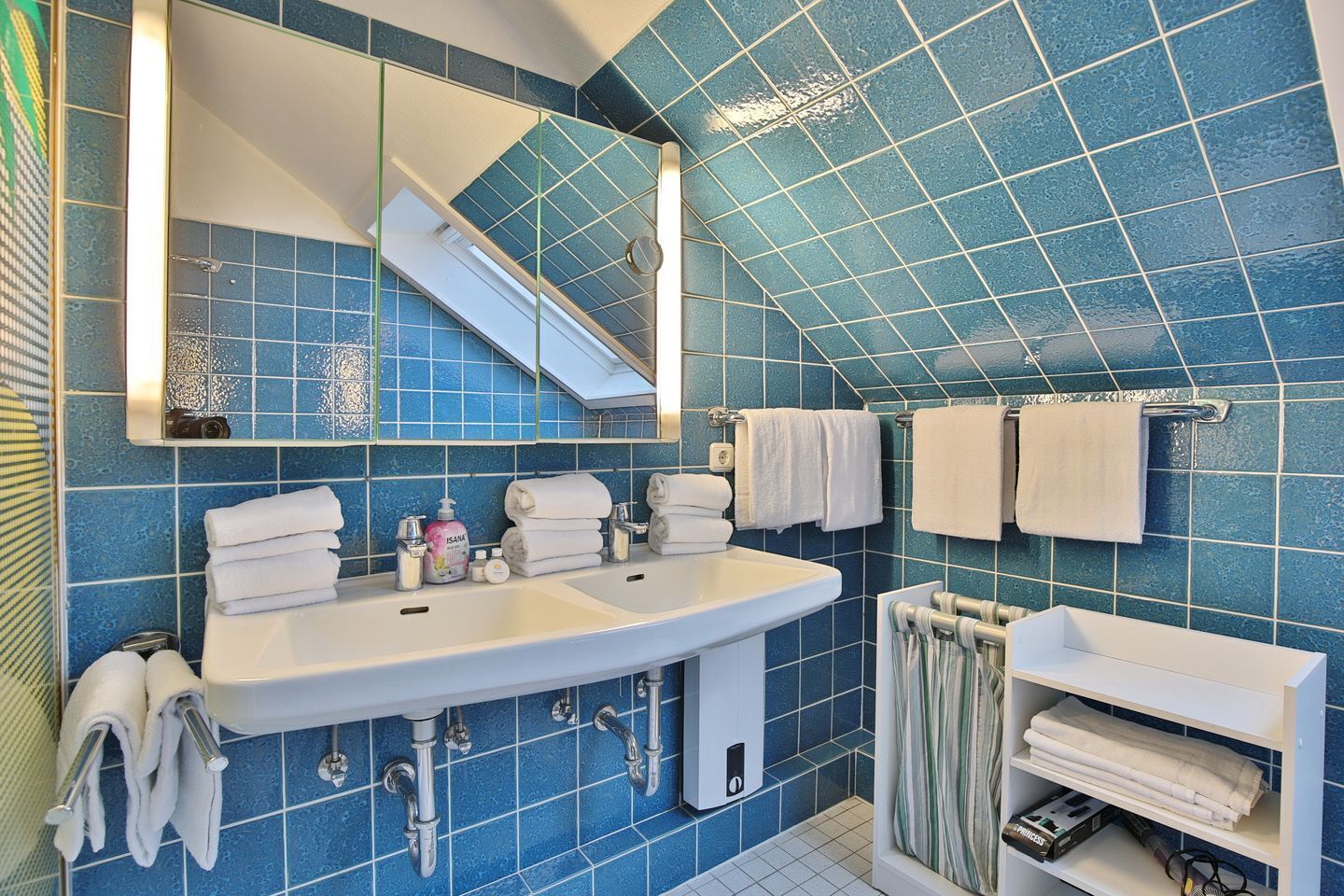 Une salle de bain avec un grand lavabo, deux miroirs et un porte-serviettes.