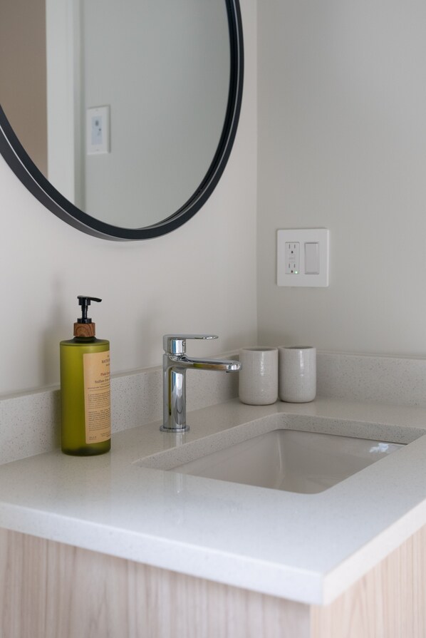 Une salle de bain avec un lavabo blanc, un miroir et un flacon de lotion.
