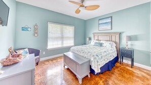 A bedroom with a bed, a nightstand, a dresser, a ceiling fan, and a window with blinds.