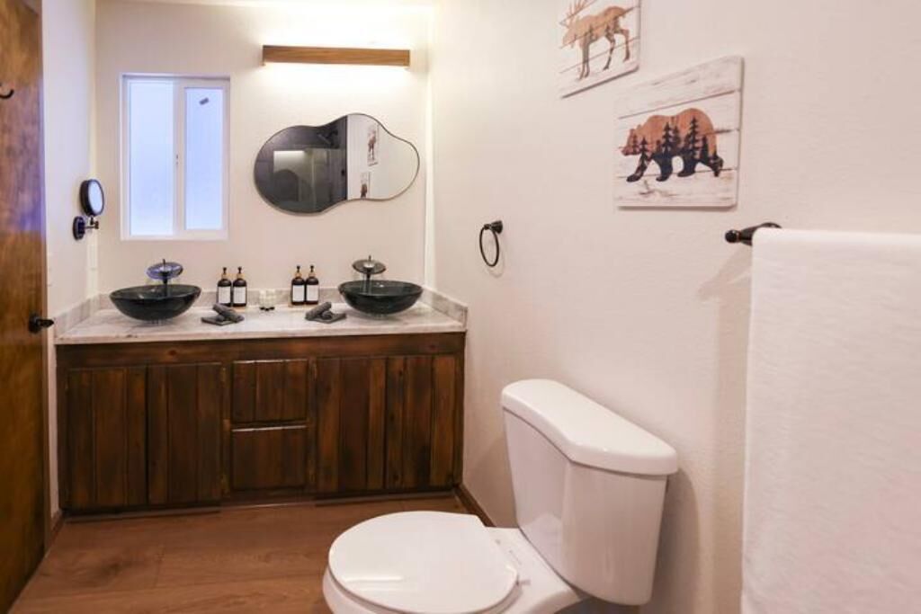 A bathroom with a wooden vanity, a white toilet, and a window.
