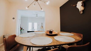A dining area with a round wooden table, white placemats, and a chandelier.