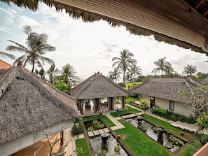 A resort with thatched-roof huts, a central courtyard with a water feature, and lush greenery.