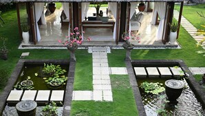 A tranquil garden with a thatched-roof pavilion, two small ponds with lily pads, and a pathway leading to the pavilion. - Villa Tanju by Elite Havens (Cemagi)