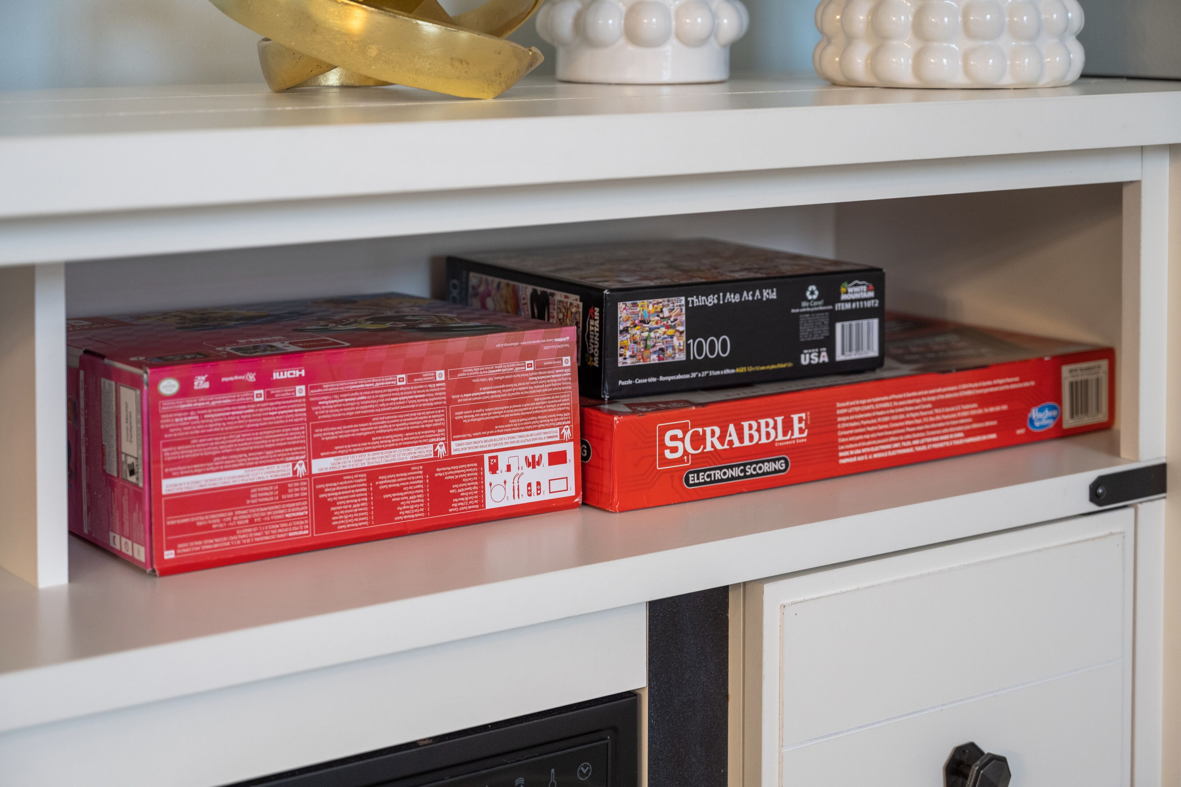 Un estante con dos cajas de Scrabble y una caja de mil piezas.