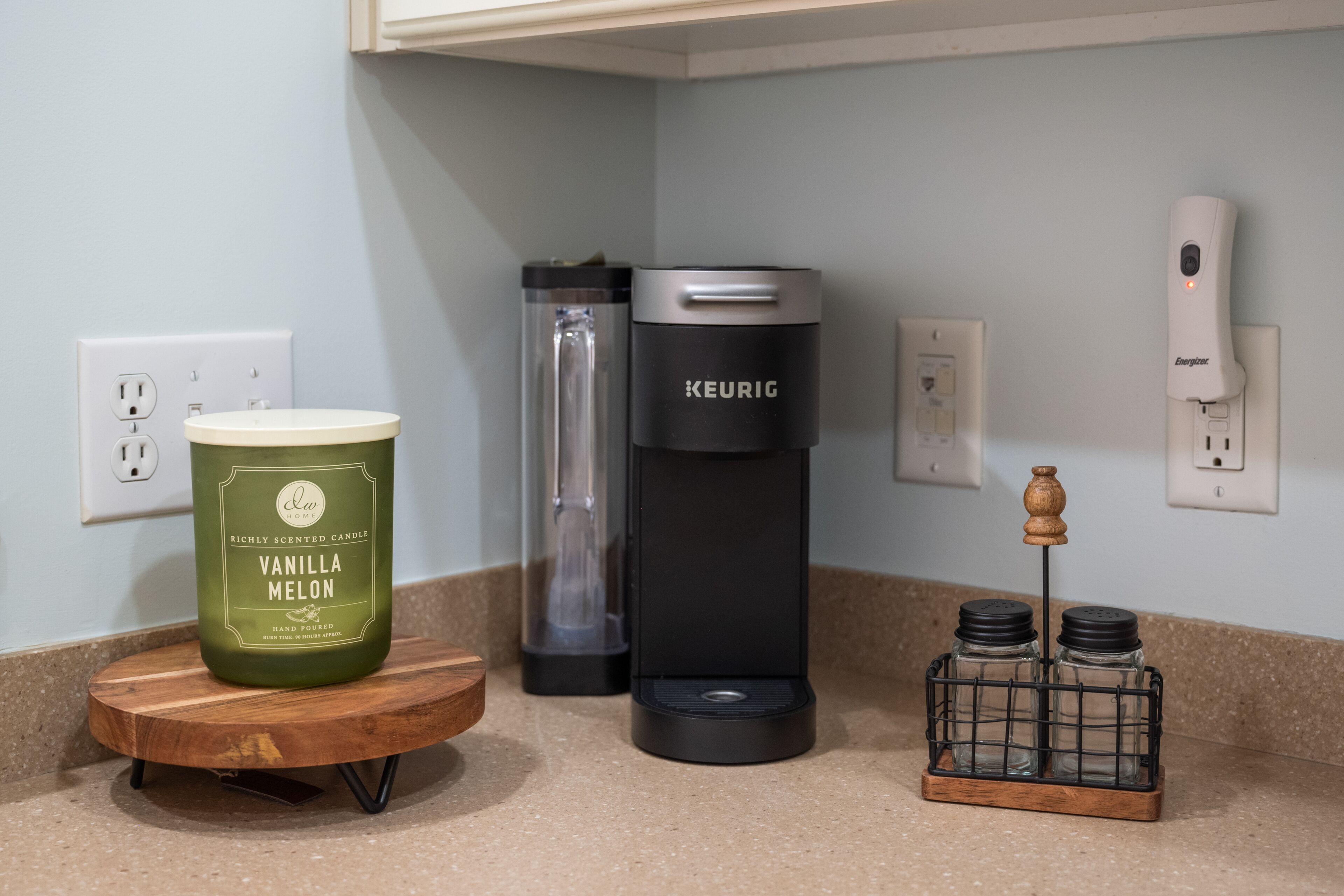 A kitchen counter with a hand-formed vanilla melon candle, a KEURIG coffee maker, and a salt and pepper shaker set.