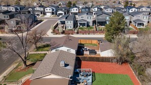 A residential area with modern houses, a well-maintained lawn, and a clear view of distant mountains.