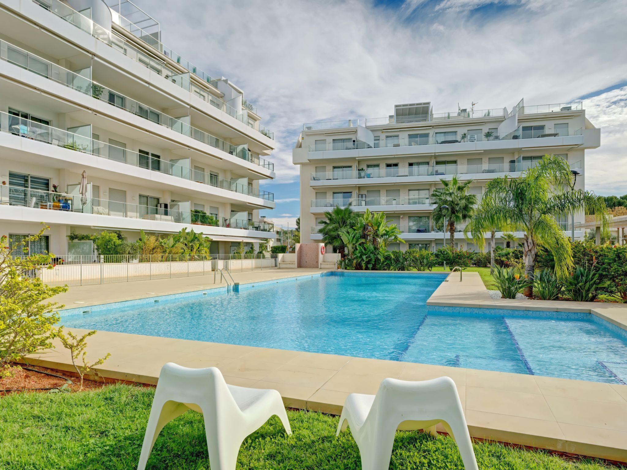 Ein modernes Hotel mit Schwimmbad, mehreren Balkonen und üppiger Bepflanzung.
