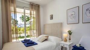 Ein Hotelzimmer mit Bett, Nachttisch, Sessel und einem Fenster mit Vorhängen.
