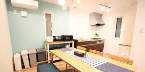 Una cocina compacta con microondas, tostadora y lavabo. Hay una mesa de comedor con un banco y un ventanal pequeño.