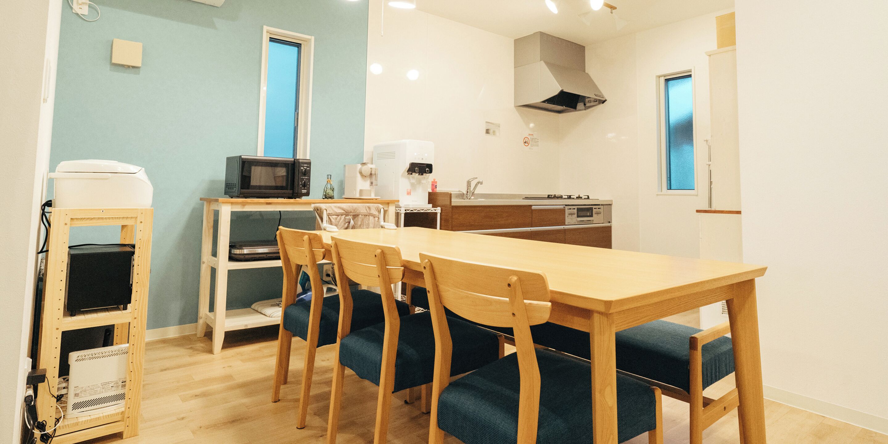 A compact kitchen with a dining table and chairs, a microwave, coffee machine, and a dishwasher.