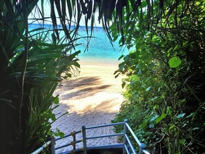 A beach pathway leading to a sandy beach with clear blue water in the background. - besuinonnasonokinawa (Onna)