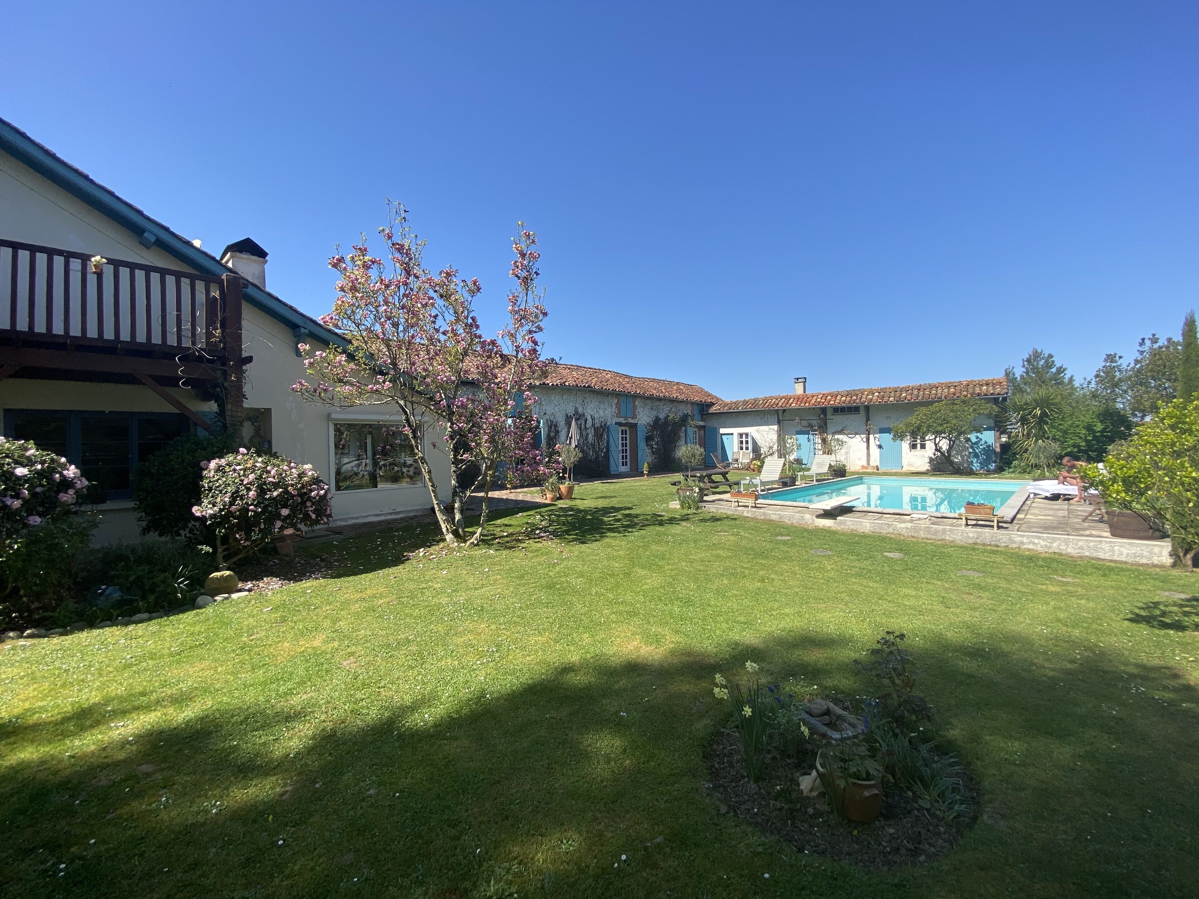 Um imóvel residencial com piscina, gramado bem cuidado e área de jardim.