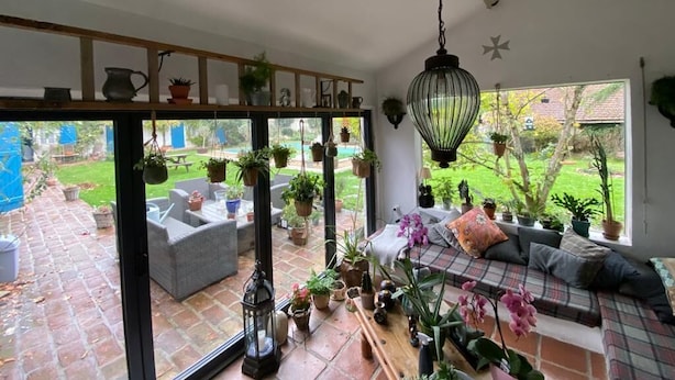 Una habitación acogedora con un gran ventanal, un sofá y varias macetas con plantas.
