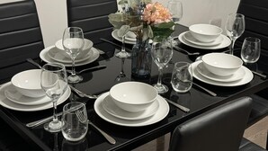 A dining table set for four with white plates, glasses, and cutlery.