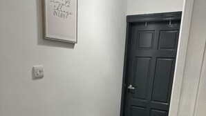 A hallway with a white radiator, a black door, and a framed inspirational quote on the wall.