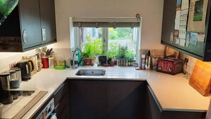 A modern kitchen with a built-in sink, a window with blinds, and various kitchen appliances and utensils.