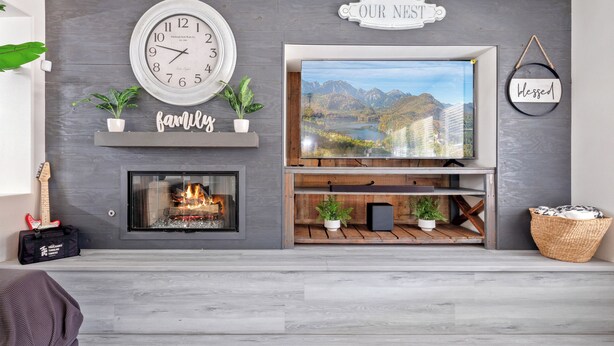 Una sala de estar con chimenea, un reloj, un televisor y un letrero que dice 