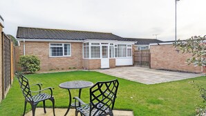 A house with a conservatory, a fenced backyard, and a patio with two chairs and a table. - Marine Lodge -  a bungalow that sleeps 4 guests  in 2 bedrooms (Bognor Regis)