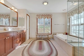 A bathroom with a wooden vanity, a large mirror, a bathtub, and a window with a view. - Mountain View Estate with Game Room & Valley Views (Quechee)