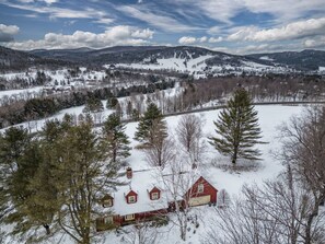 A rural landscape with a red barn, snow-covered fields, and distant mountains. - Mountain View Estate with Game Room & Valley Views (Quechee)
