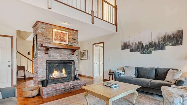 Amplia sala de estar con chimenea, un sofá, una mesa de centro y una escalera.