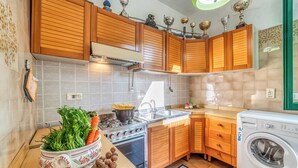 Una cocina con armarios de madera, estufa, fregadero y lavadora.