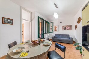 Un espace repas avec une table ronde, des chaises et un canapé en arrière-plan.
