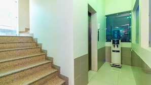 A clean, well-lit hallway with a water dispenser and a glass elevator. - Minh Phương HBC Hotel - by Bay Luxury (Ho Chi Minh City)