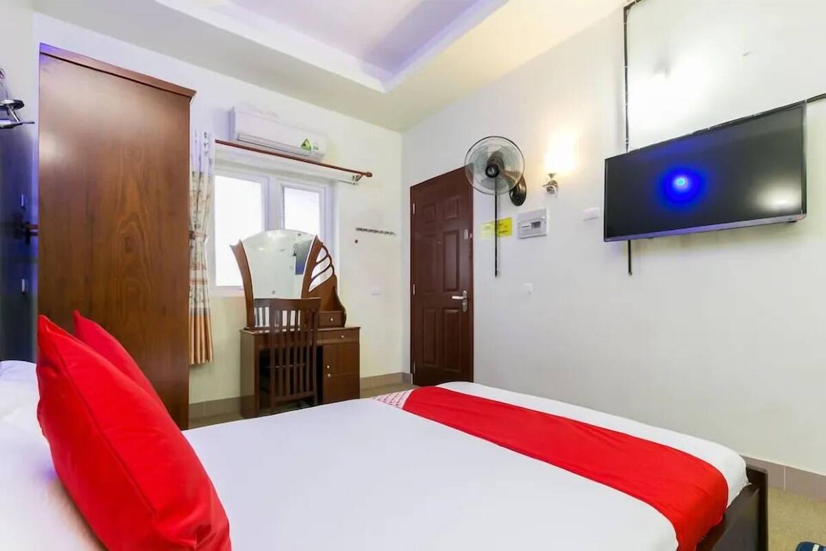Et hotelværelse med seng, fjernsyn, ventilator og skab.