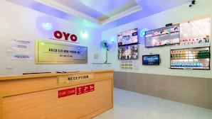 A reception area with a wooden desk labeled "RECEPTION," a sign for "KHÁCH SAN MINHUI HỌC," and a digital screen displaying various content. - Minh Phương HBC Hotel - by Bay Luxury (Ho Chi Minh City)