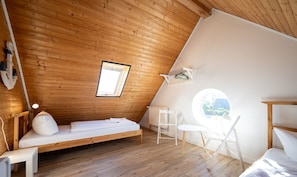 A small, wooden-paneled room with a single bed, a white chair, and a small table. - Ferienhaus Look - Ferienhaus Look auf der Insel Rügen (Garz/Rügen)