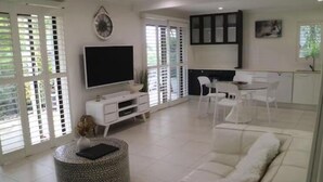 Un soggiorno moderno con divano, tavolino e televisore. È presente anche un'area pranzo con sedie e tavolo.