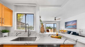 Una cocina moderna con una isla grande, electrodomésticos de acero inoxidable y vistas al exterior.